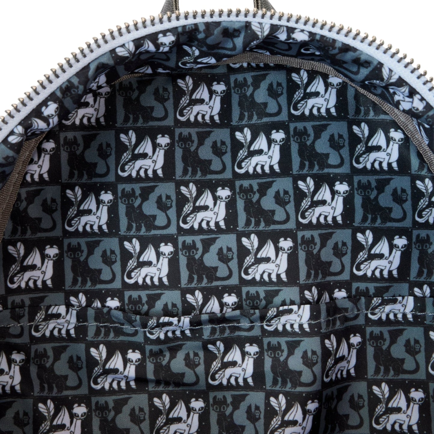 Close-up of a bag with a pattern of black and white Light and Night Fury dragons on a dark background.