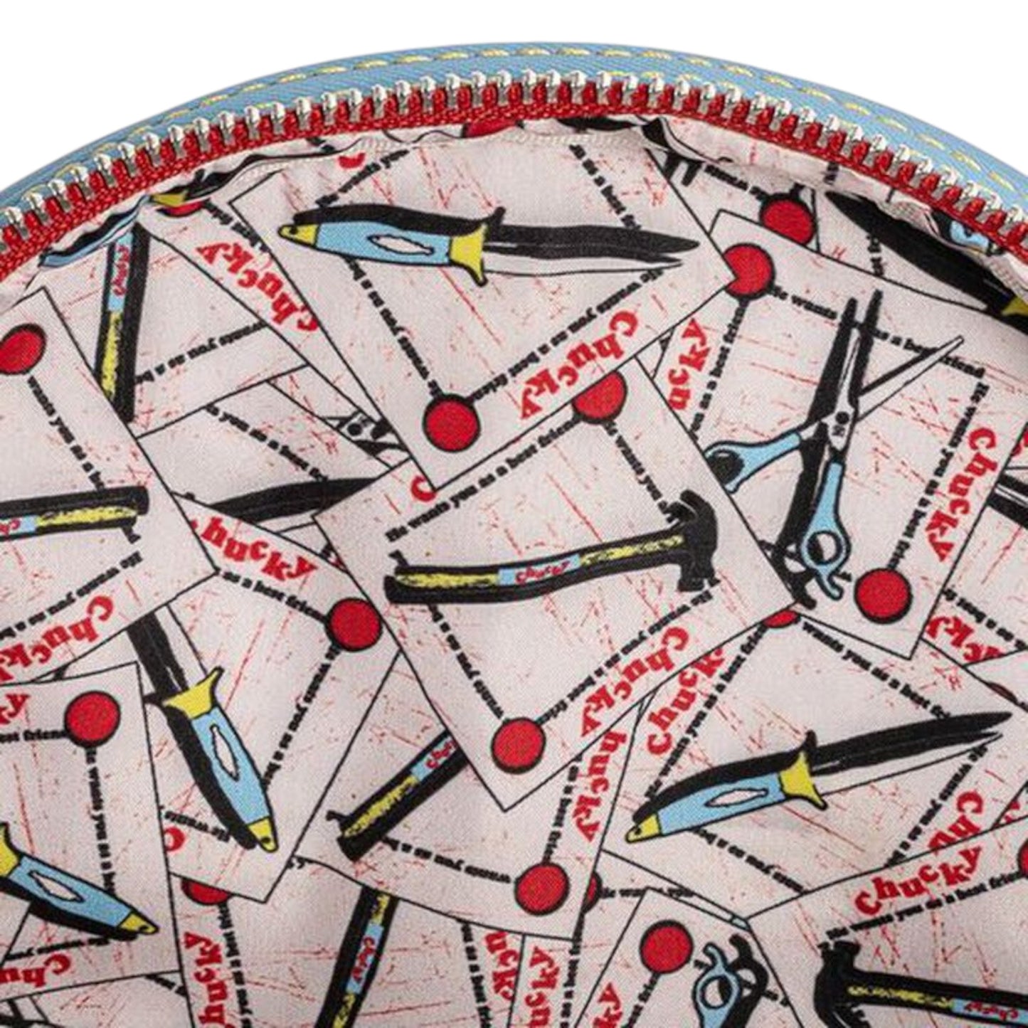 Close-up of inside of Loungefly Child's Play Chucky Cosplay Mini Backpack with a knife, hammer, scissors, and Chucky text patterned fabric design on a white background