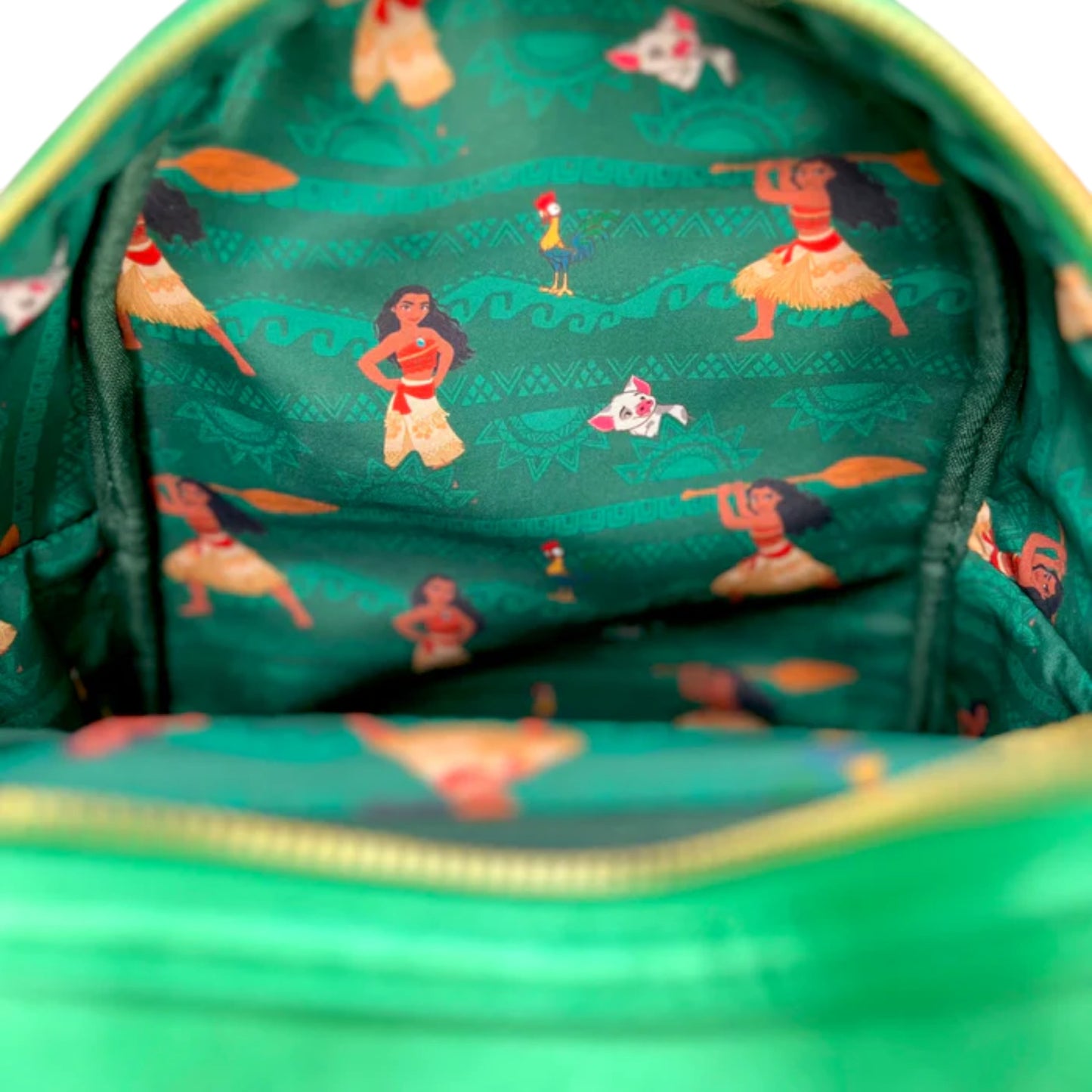 Close-up of a inside of Green Loungefly Disney Moana Heart of Te Fiti Sequin Glow Mini Backpack with Moana and other character designs pattern on a greenbackground