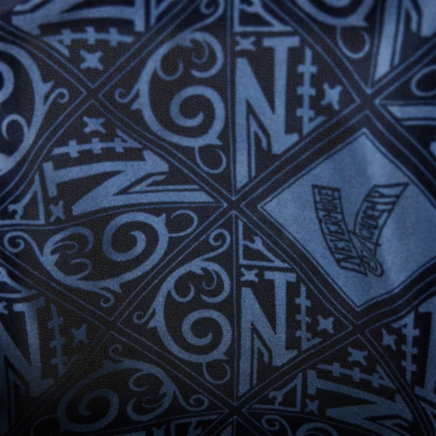Close-up of a patterned fabric with 'N" text and symbols on a dark background