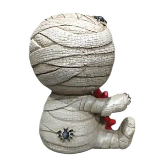 Skeleton face mummy figurine with a red gummy bear on a white background