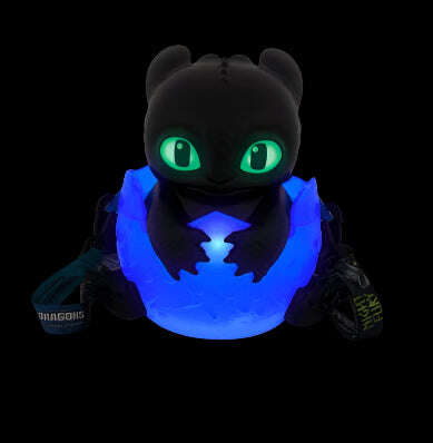 Toothless, from How to Train Your Dragon, popcorn bucket with glowing blue chest and green eyes on a black background