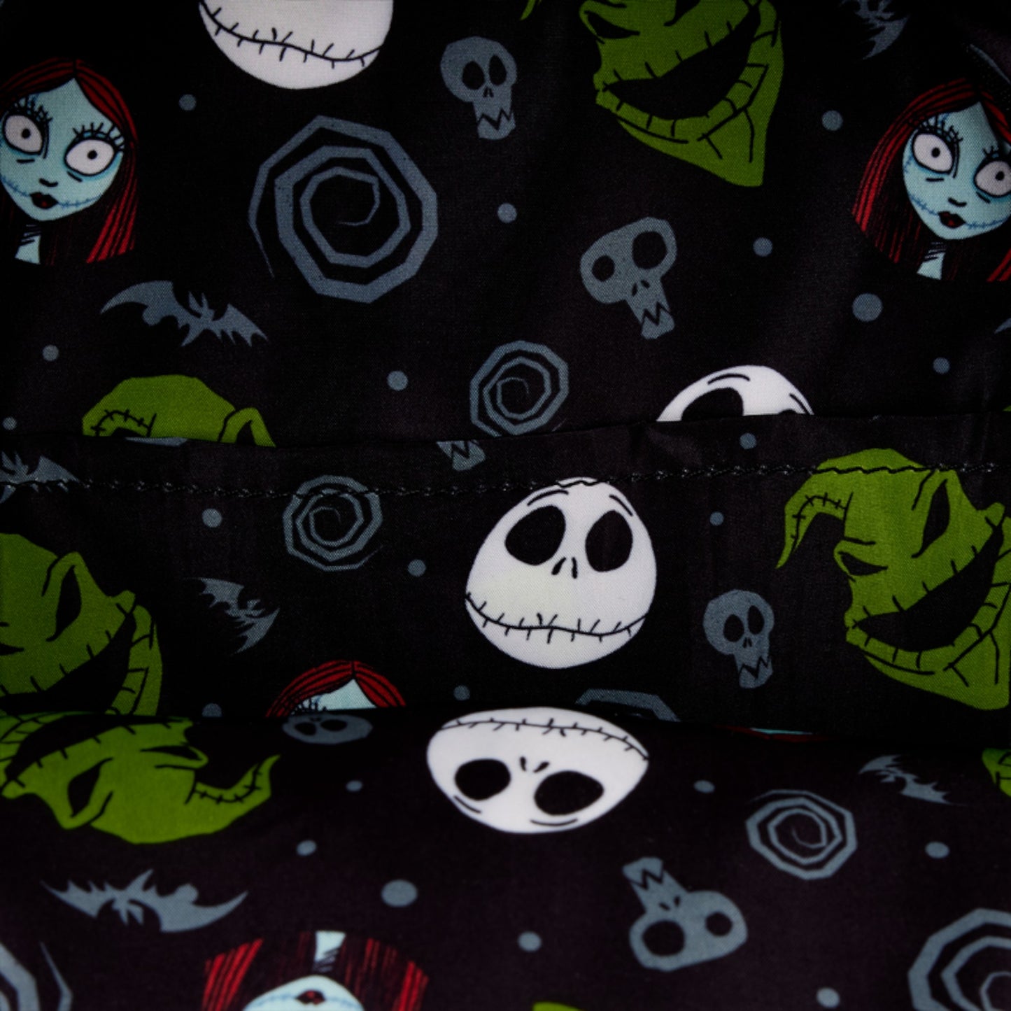 Inside of Loungefly Disney The Nightmare Before Christmas Sally Cosplay Mini Backpack patterned fabric with NBC characters and elements from 'The Nightmare Before Christmas' on a dark background.
