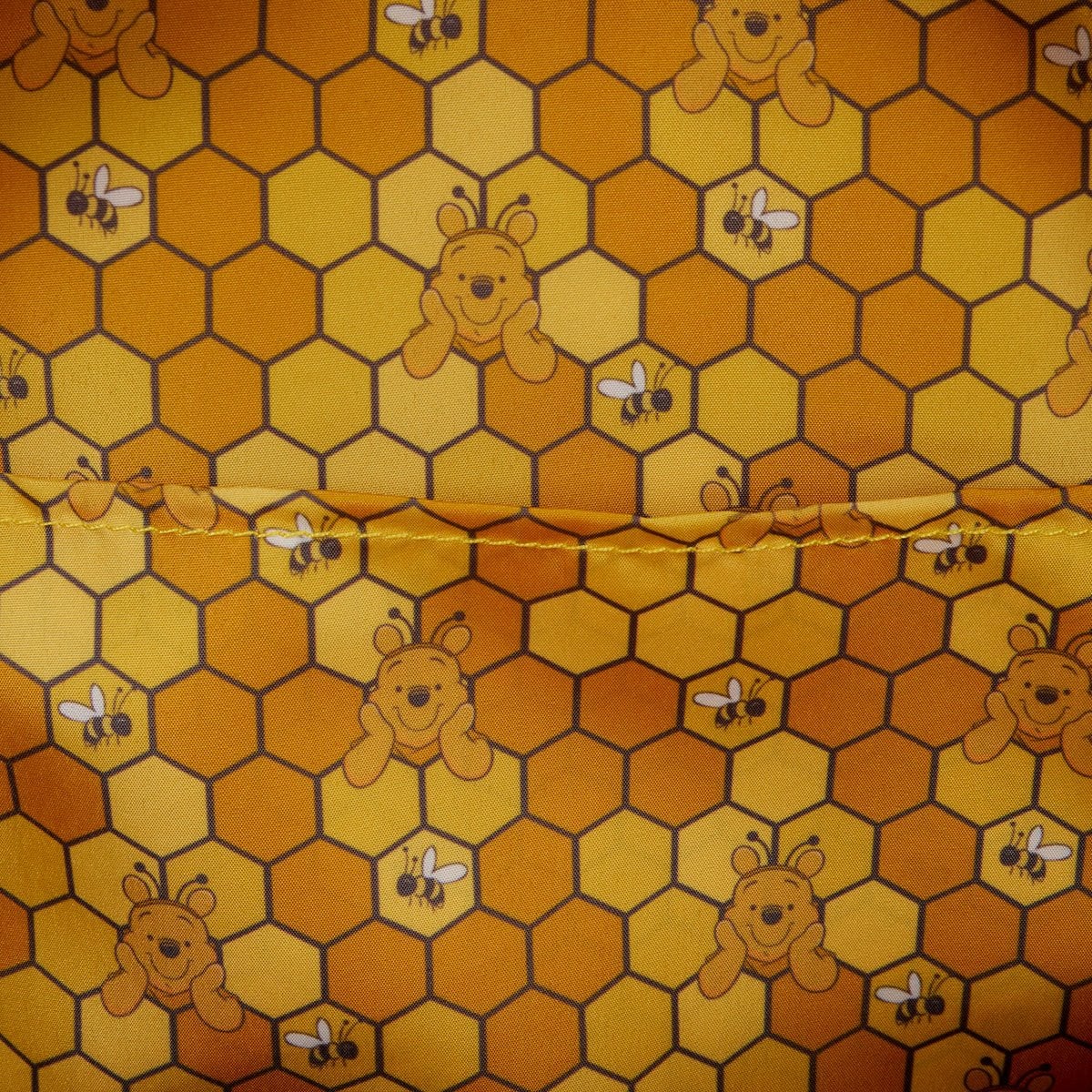 Fabric with honeycomb pattern featuring winnie the pooh and bees on a yellow background