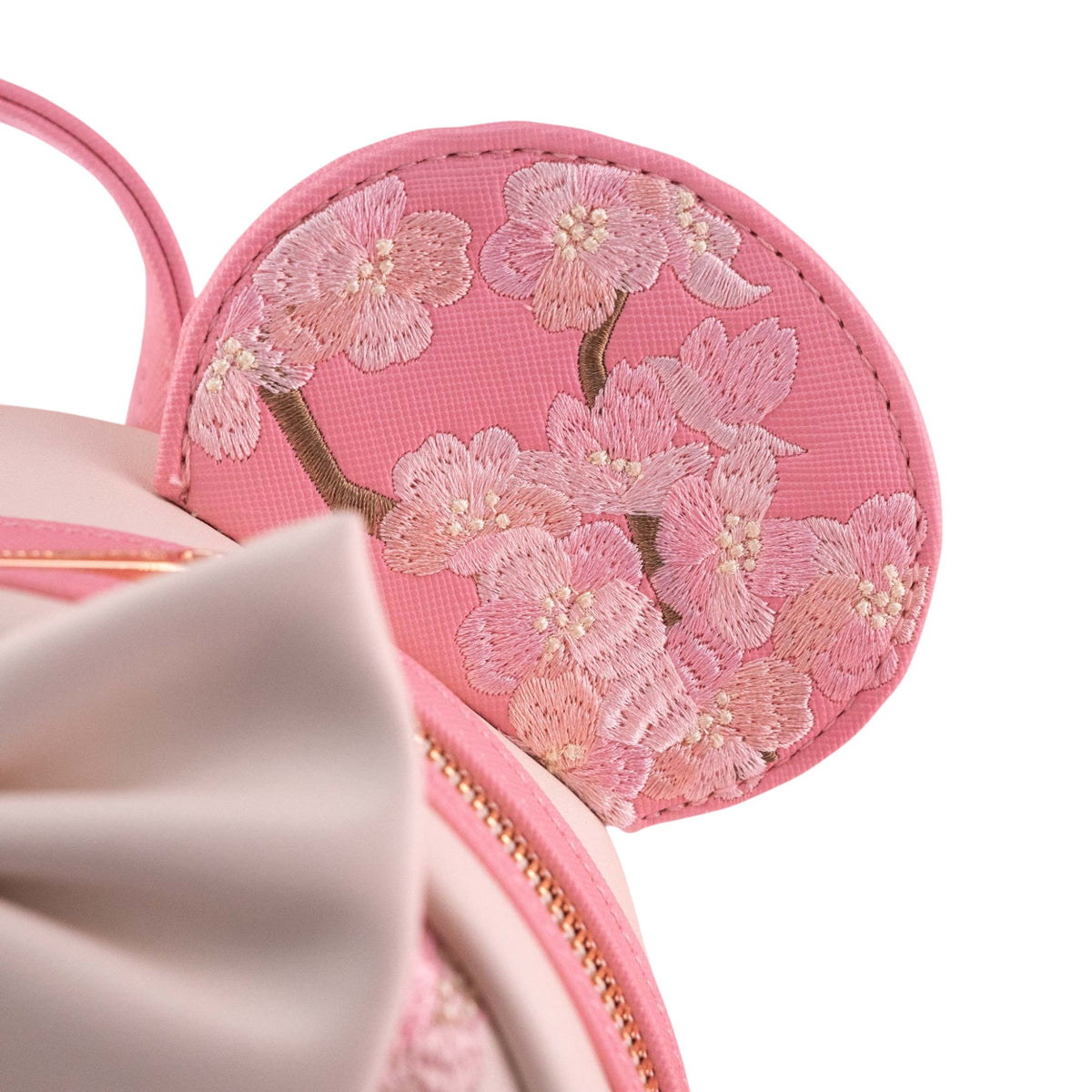 Close-up of bag's minnie mouse pink ear with floral embroidery on a white background