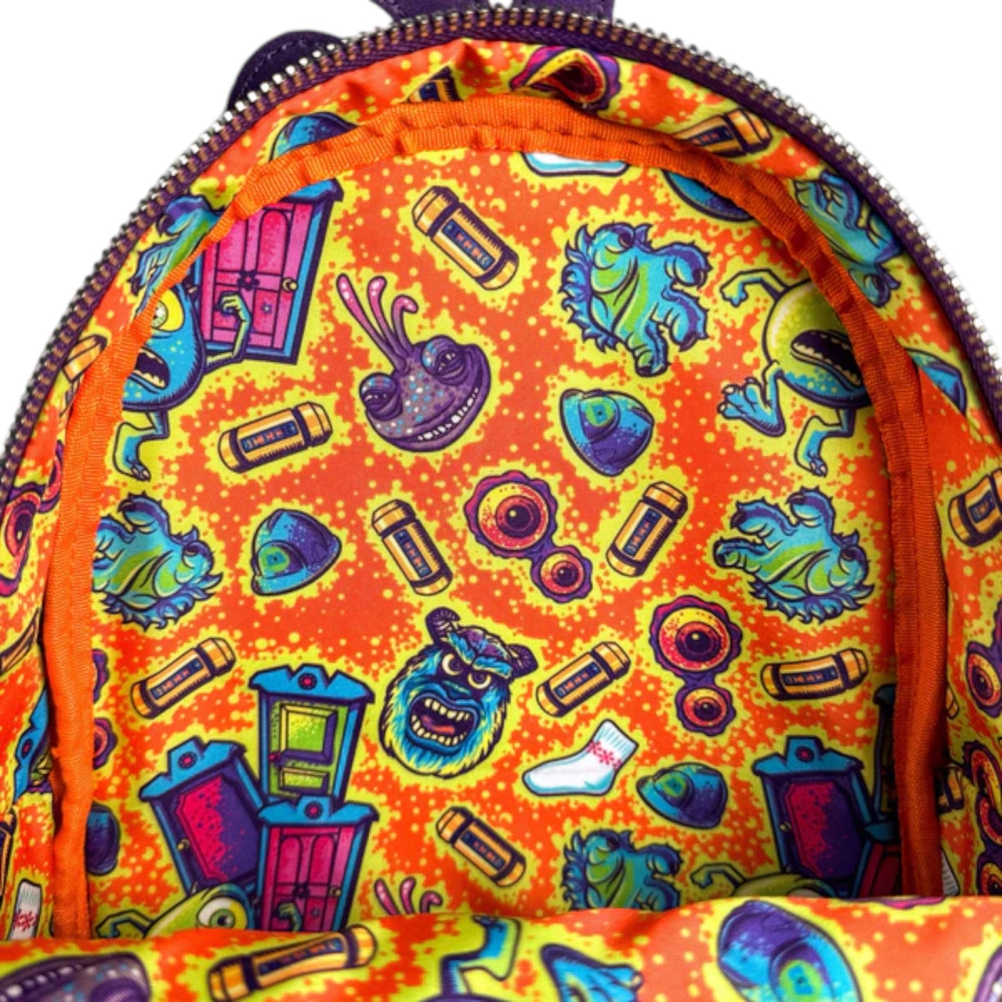 Colorful backpack with monsters inc character-themed design on an orange background
