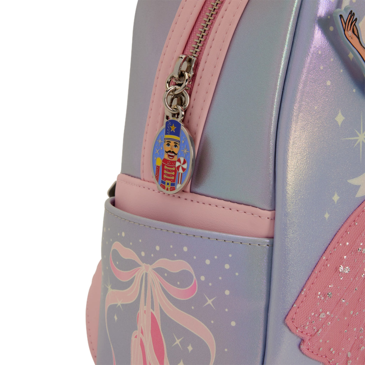 Close-up of a pastel backpack with a lavender and pink body, a pink zipper, and a dangling nutcracker charm on a white background.