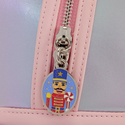 Close-up of a pastel pink and lavender bag with a silver zipper and a colorful nutcracker-themed oval zipper pull.