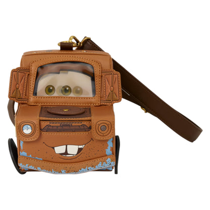 A Disney Cars Mater crossbody bag designed to look like the character Mater, featuring a brown faux-leather body, a clear window showing cartoon eyes, a gold clasp, and a matching brown shoulder strap on a white background.