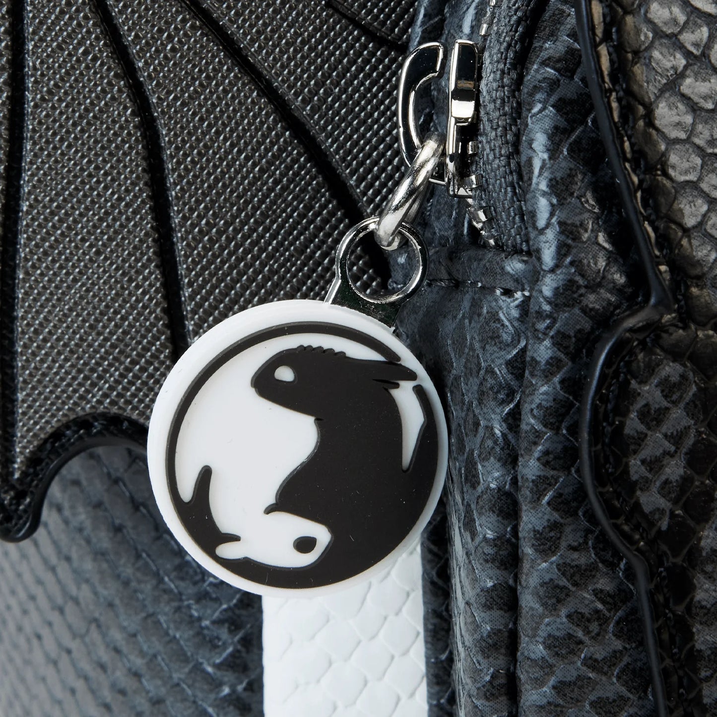 Close-up of a bag with a Light and Night Fury charm design.