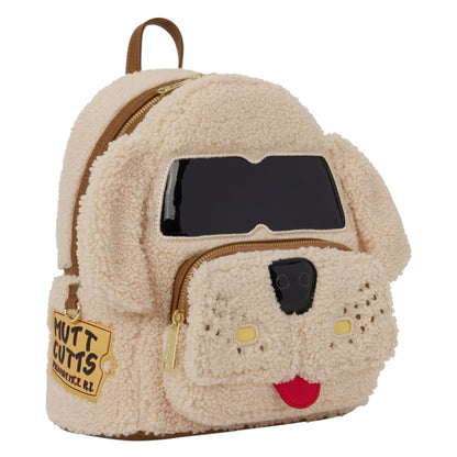 A dog-shaped teddy fleece backpack in cream beige, featuring a black faux-leather face patch, gold zippers, and a 'Mutt Cutts' patch on the side pocket, shown on a plain white background.