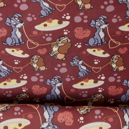 A close-up of patterned fabric featuring Lady & the Tramp with hearts, paw prints, and pizza slices on a dark red background.