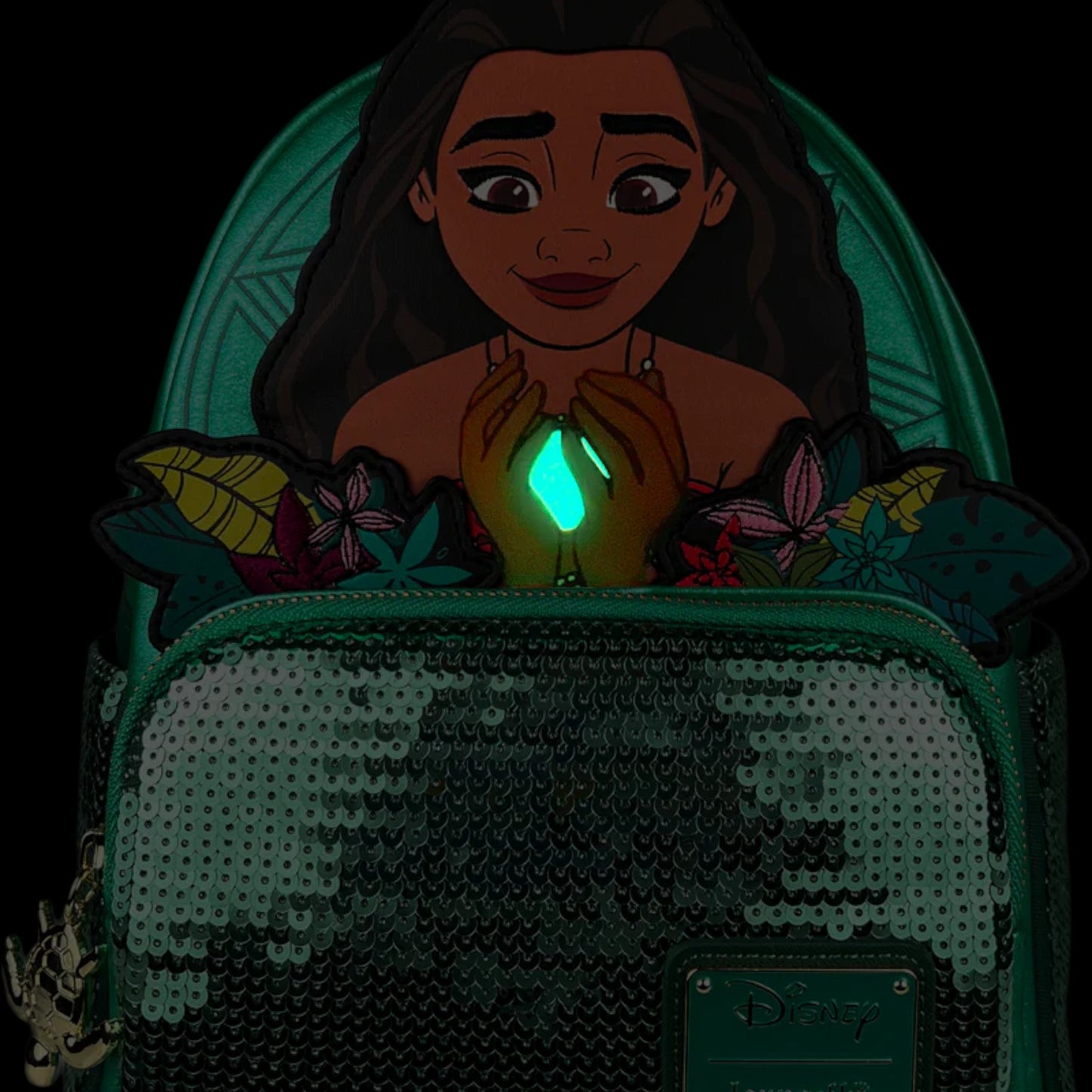 Green Loungefly Disney Moana Heart of Te Fiti Sequin Glow Mini Backpack with Moana Character design holding a glowing green gem surrounded by flowers on a white background 