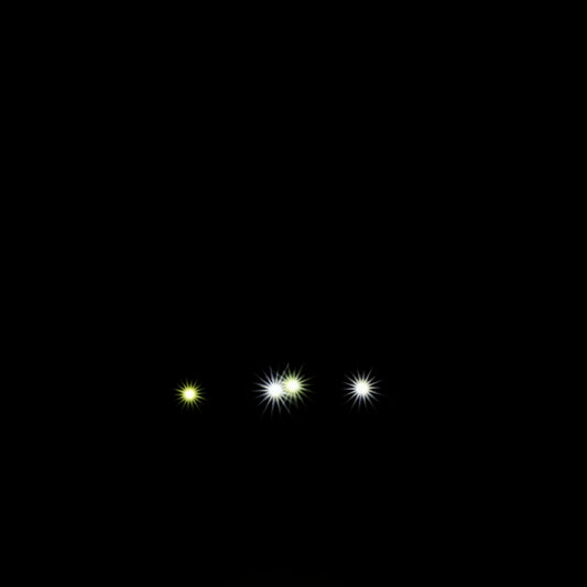 Three small glowing bright headlights on a black background
