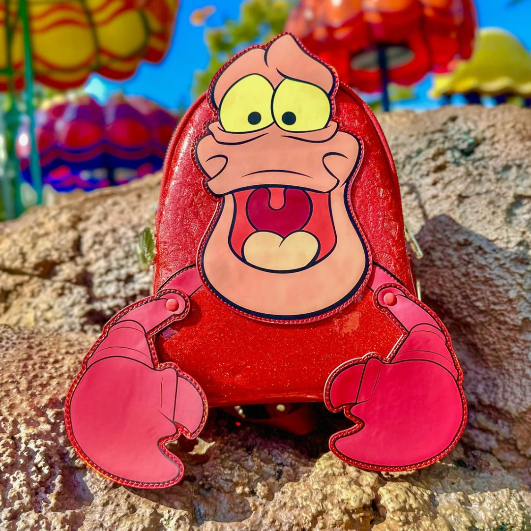 The Little Mermaid Sebastian Metallic  character with a red shell on a rocky surface with colorful background
