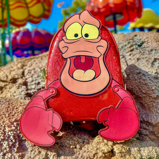 The Little Mermaid Sebastian Metallic  character with a red shell on a rocky surface with colorful background