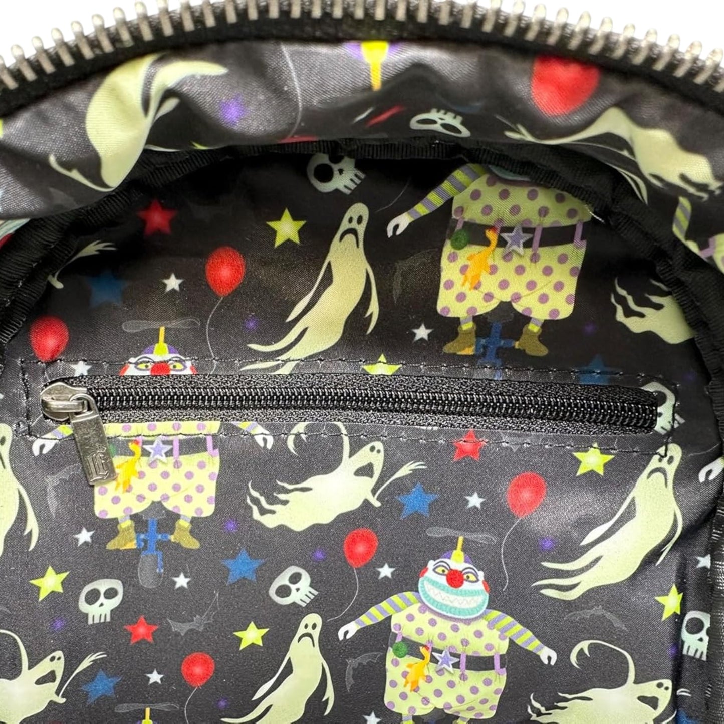 Close-up of inside of Loungefly Disney The Nightmare Before Christmas Clown Cosplay Mini Backpack with character faces and patterns on a black background