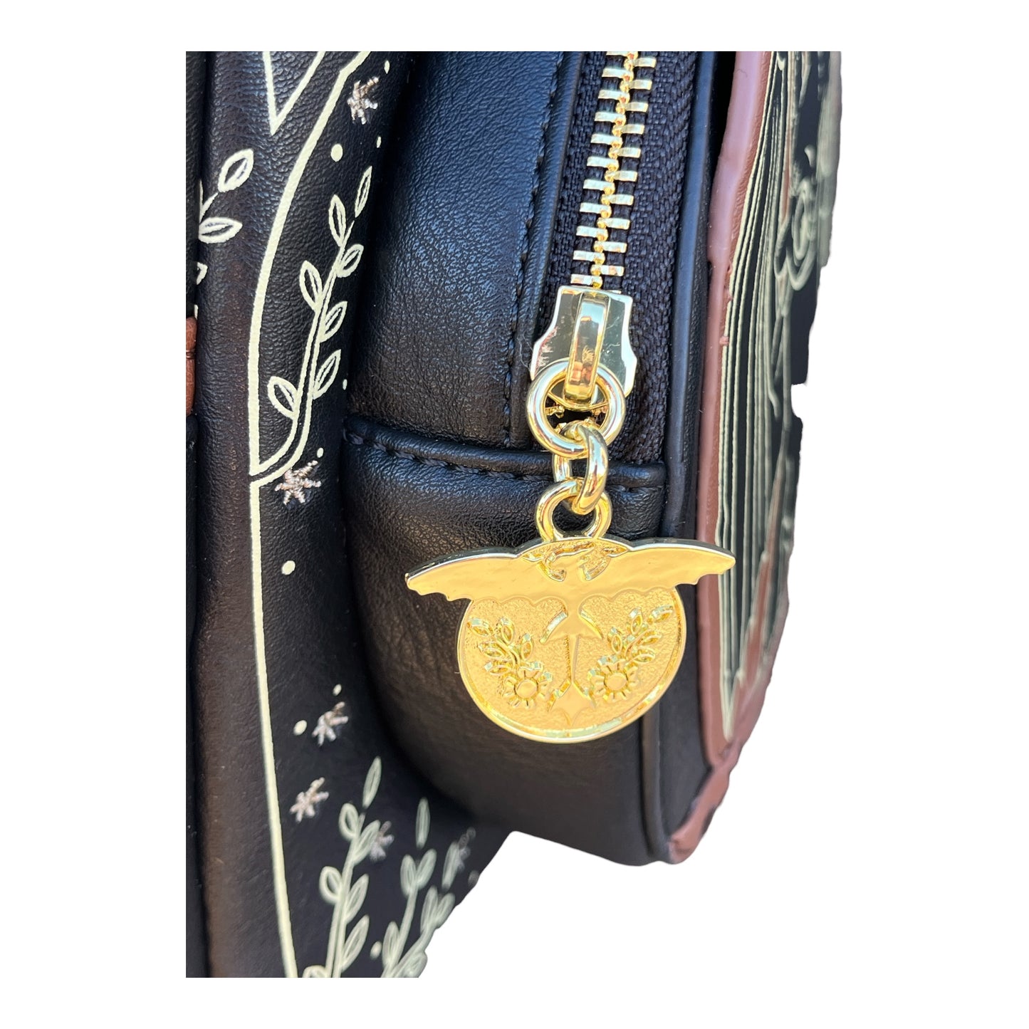 Gold dragon zipper charm on a black backpack with decorative patterns
