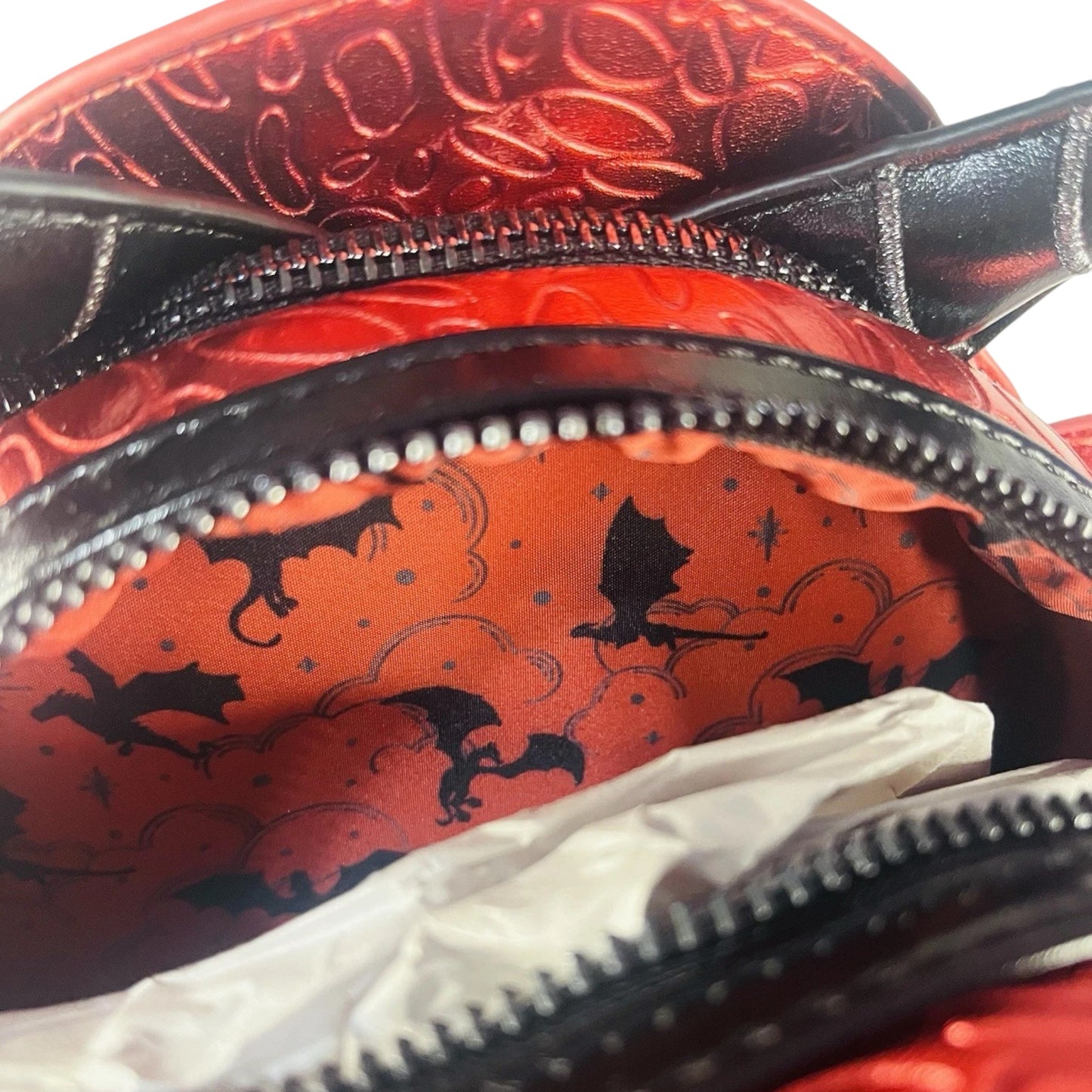 Close-up of a Red Dragon Mini Backpack with black dragon designs.
