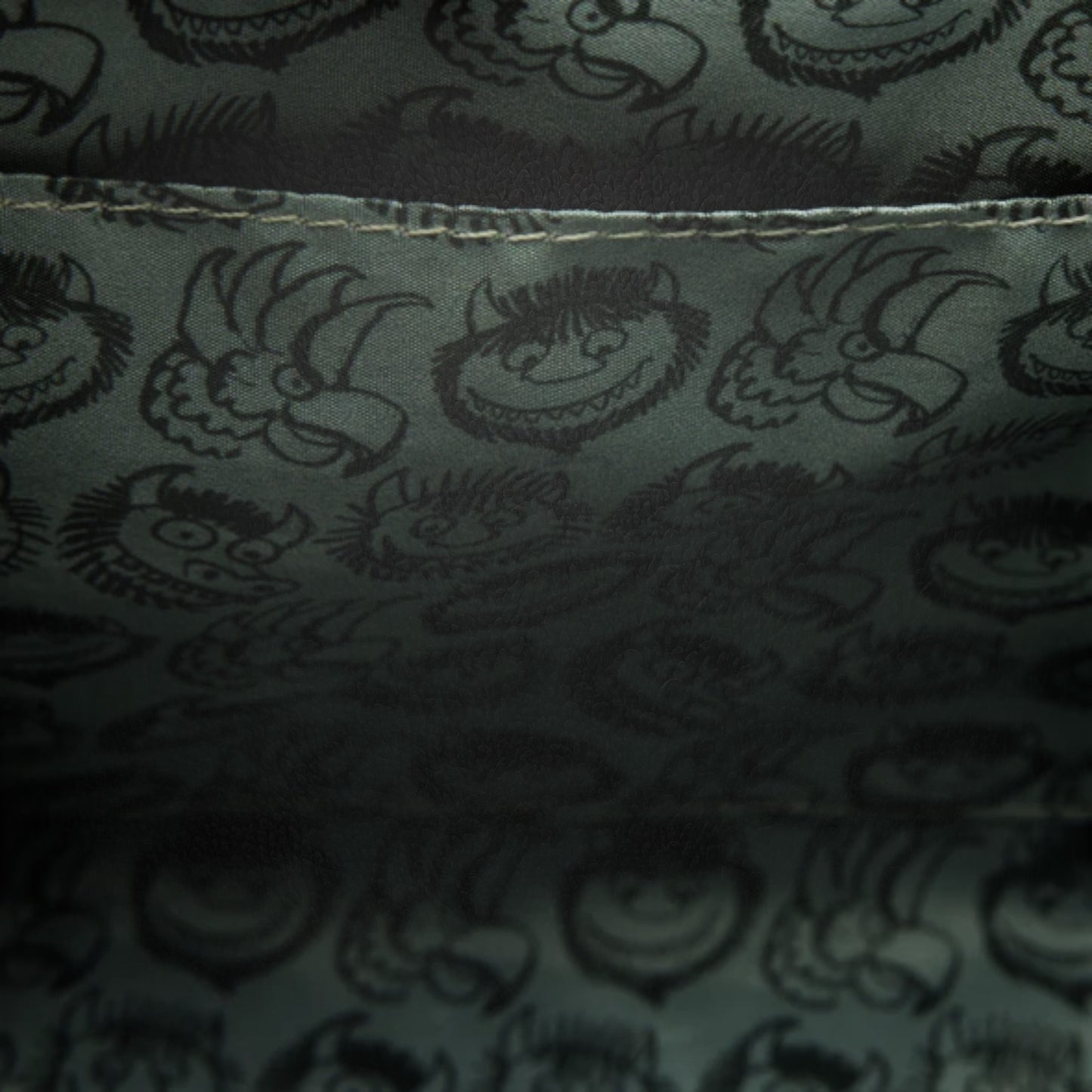 Dark fabric with printed pattern of Where the Wild Things Are faces and shapes