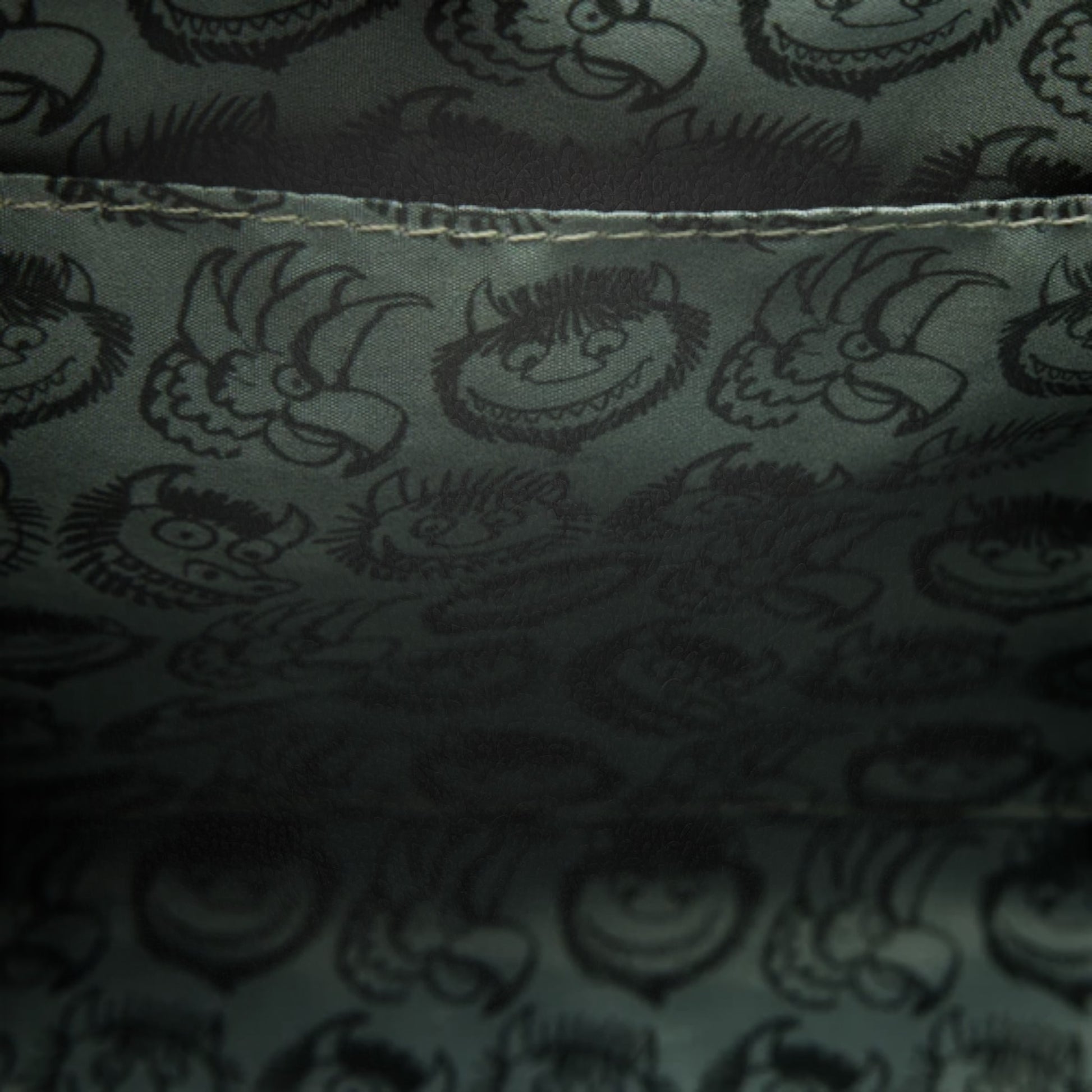 Dark fabric with printed pattern of Where the Wild Things Are faces and shapes