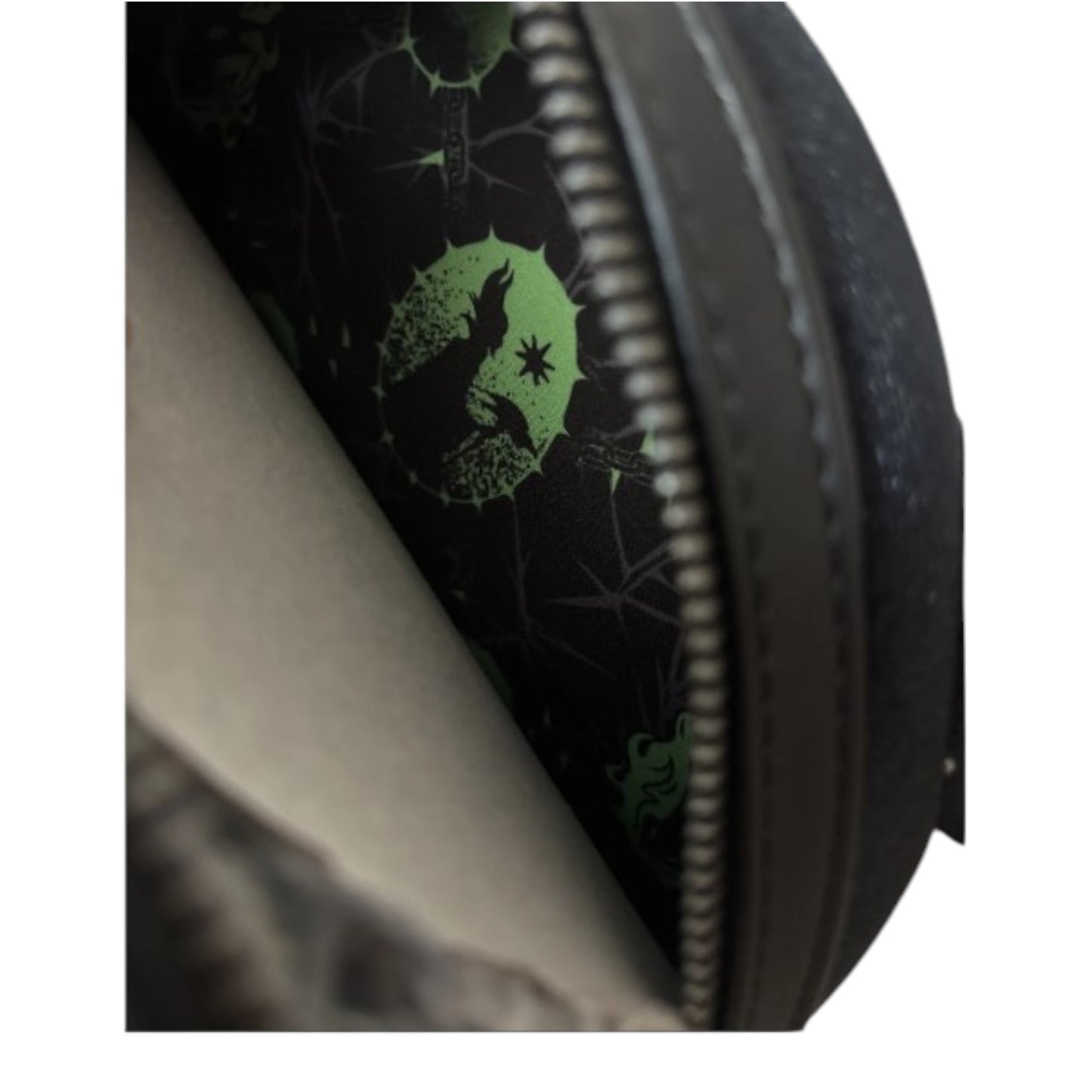 Close-up of a black bag with green Maleficent and diablo designs on a dark background