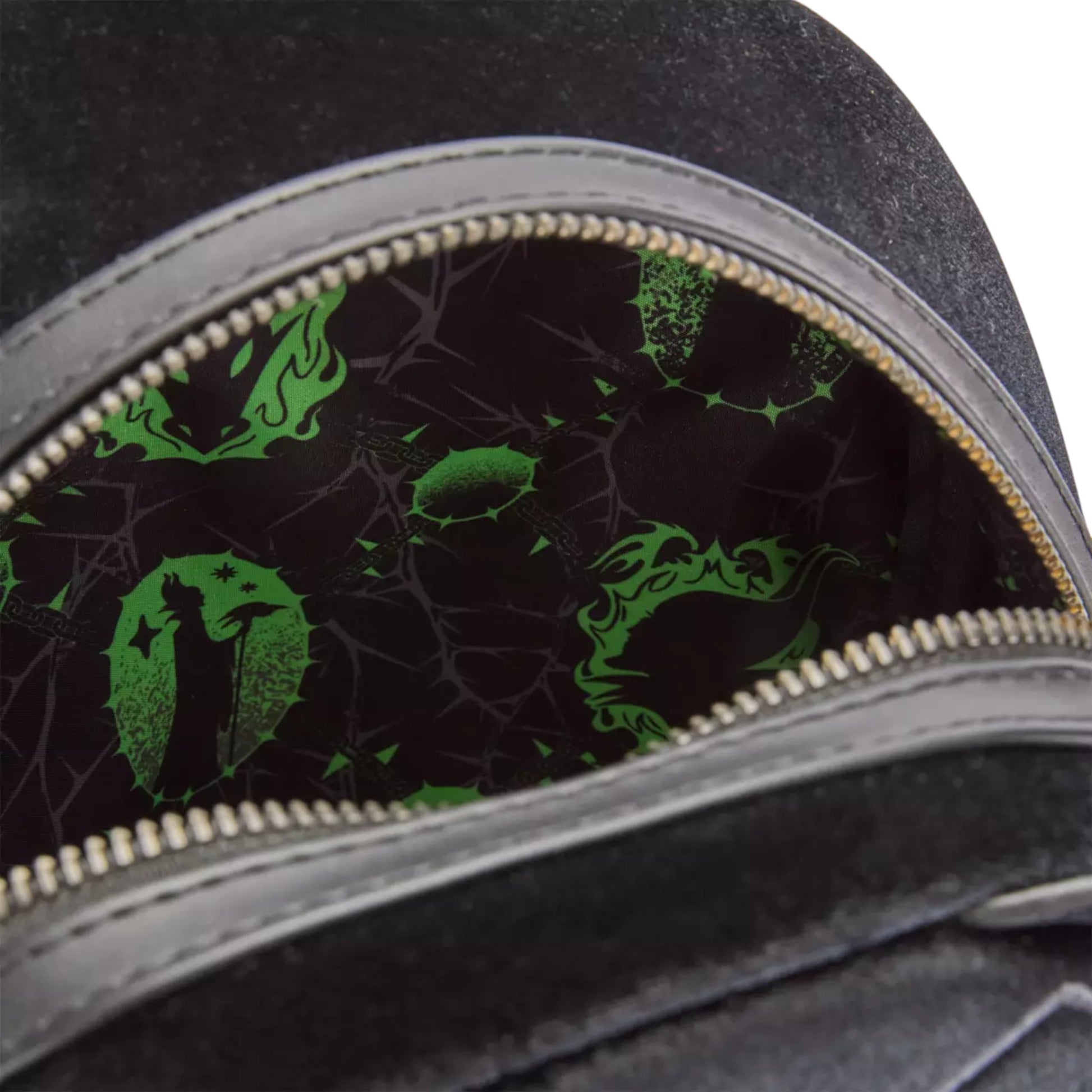 Close-up of a black Maleficent bag with green Maleficent and diablo designs on a dark background