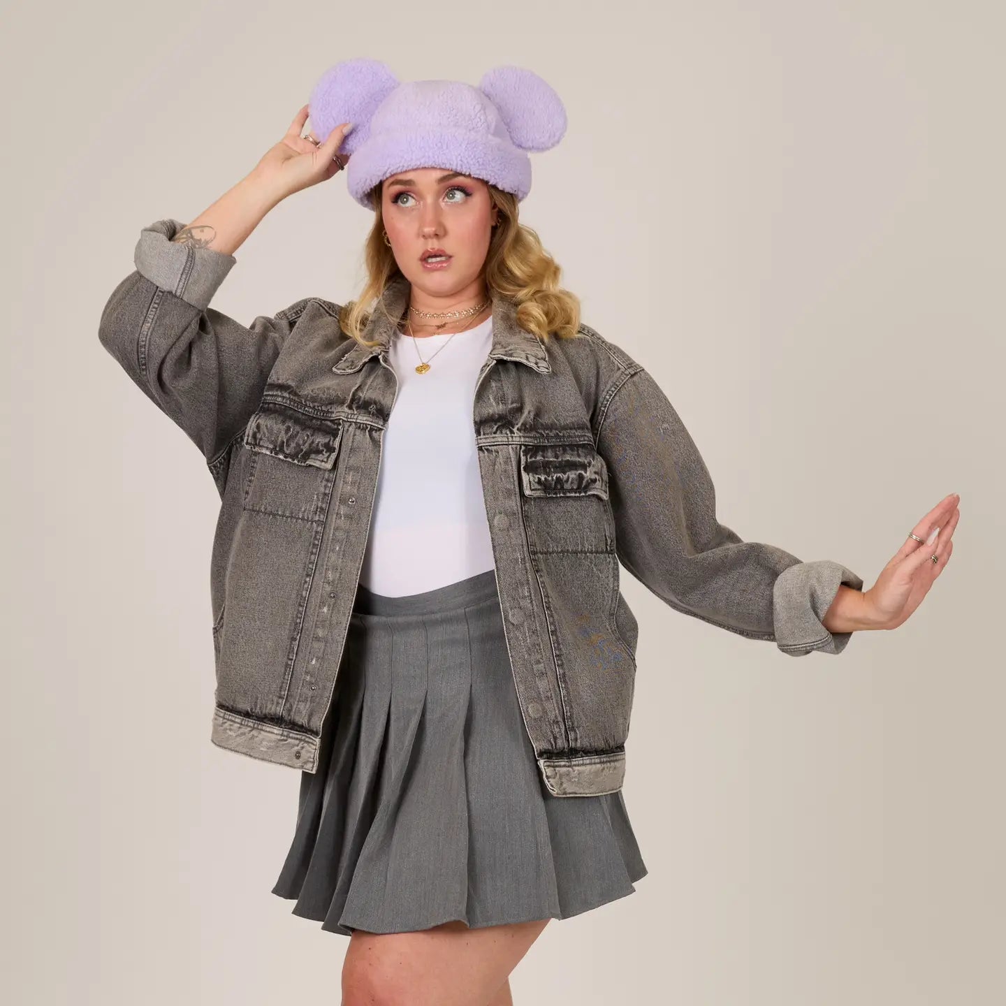 Person wearing a gray jacket, white shirt, and gray pleated skirt with a Mickey Sherpa Beanie Lavender with Mickey ears hat.