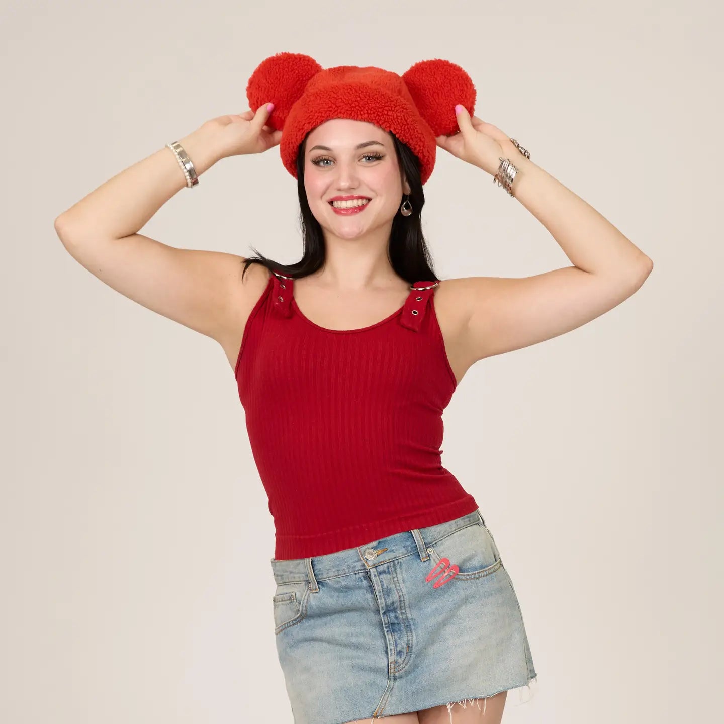 Woman wearing a Mickey Sherpa Beanie Strawberry hat with Mickey ears and a red tank top against a beige background