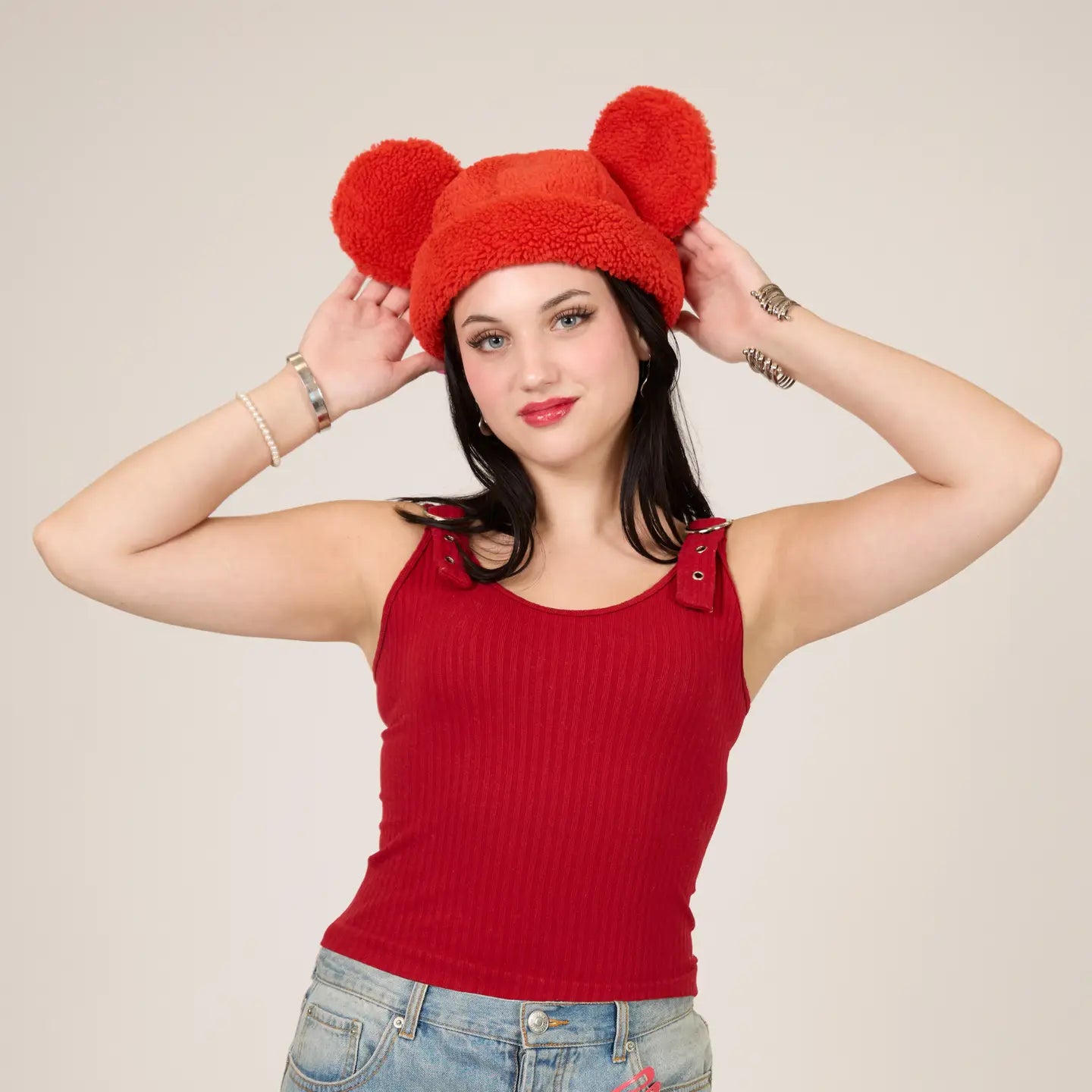 Woman wearing a Mickey Sherpa Beanie Strawberry hat with Mickey ears against a beige background