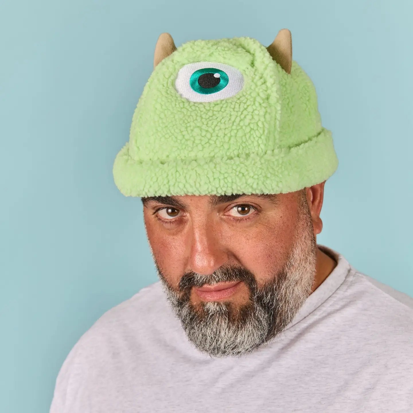 Person wearing a Mike Wazowski Sherpa Beanie with a blue background