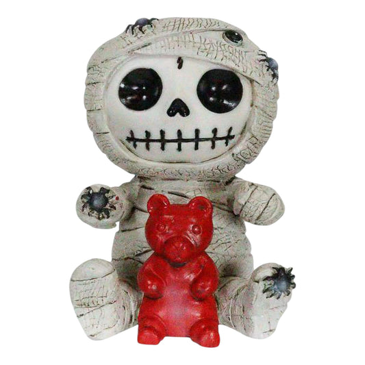 Skeleton face mummy figurine with a red gummy bear on a white background