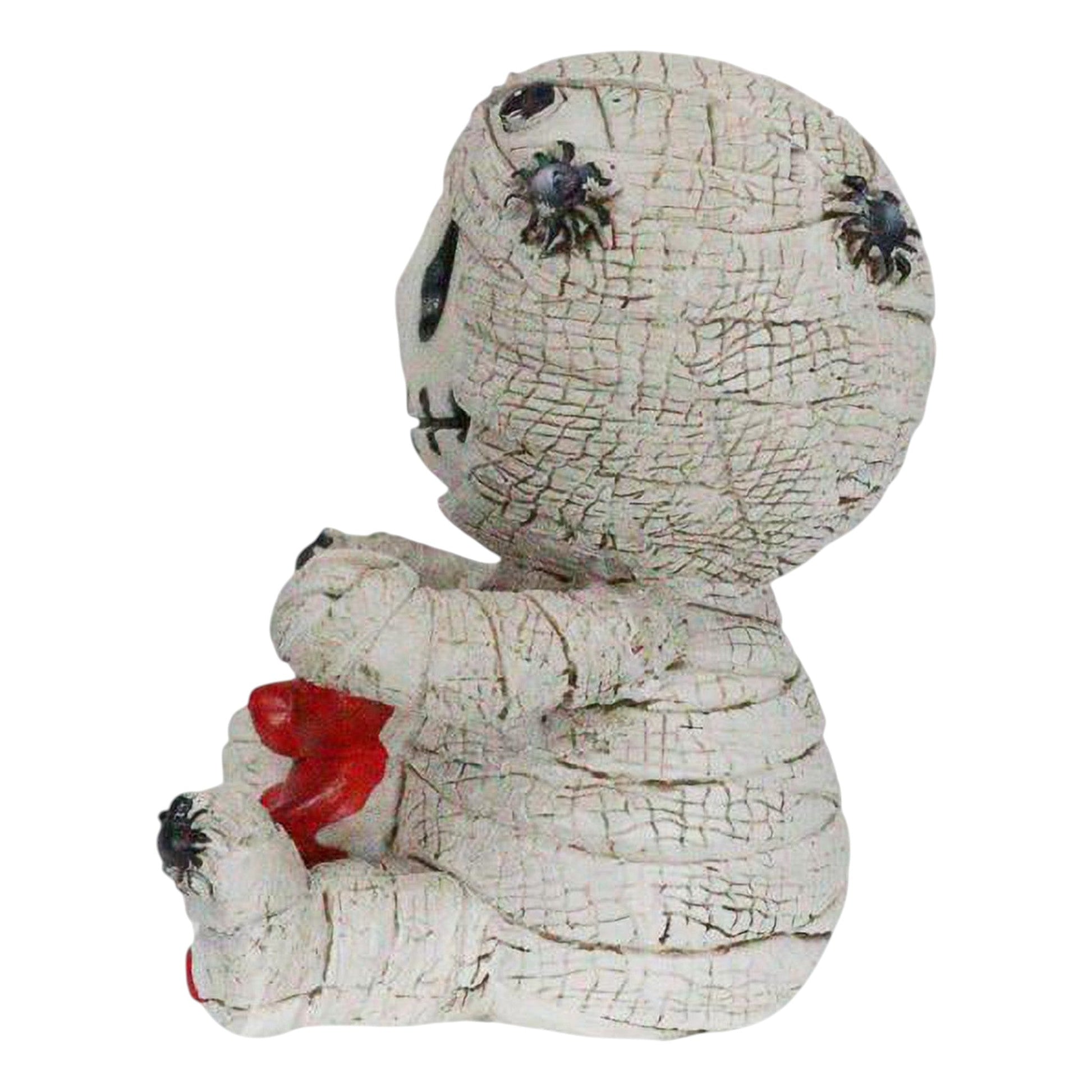 Skeleton face mummy figurine with a red gummy bear on a white background