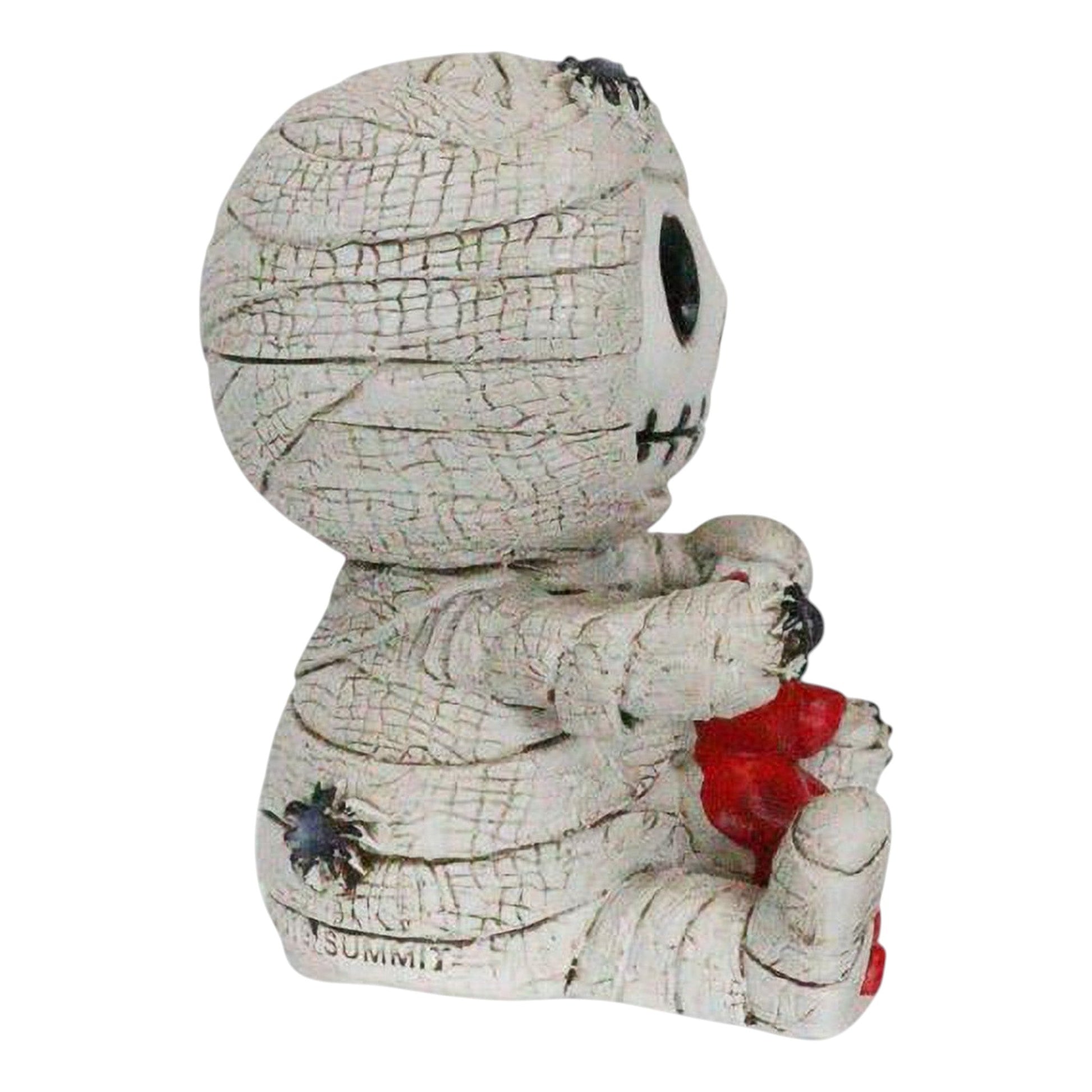 Skeleton face mummy figurine with a red gummy bear on a white background