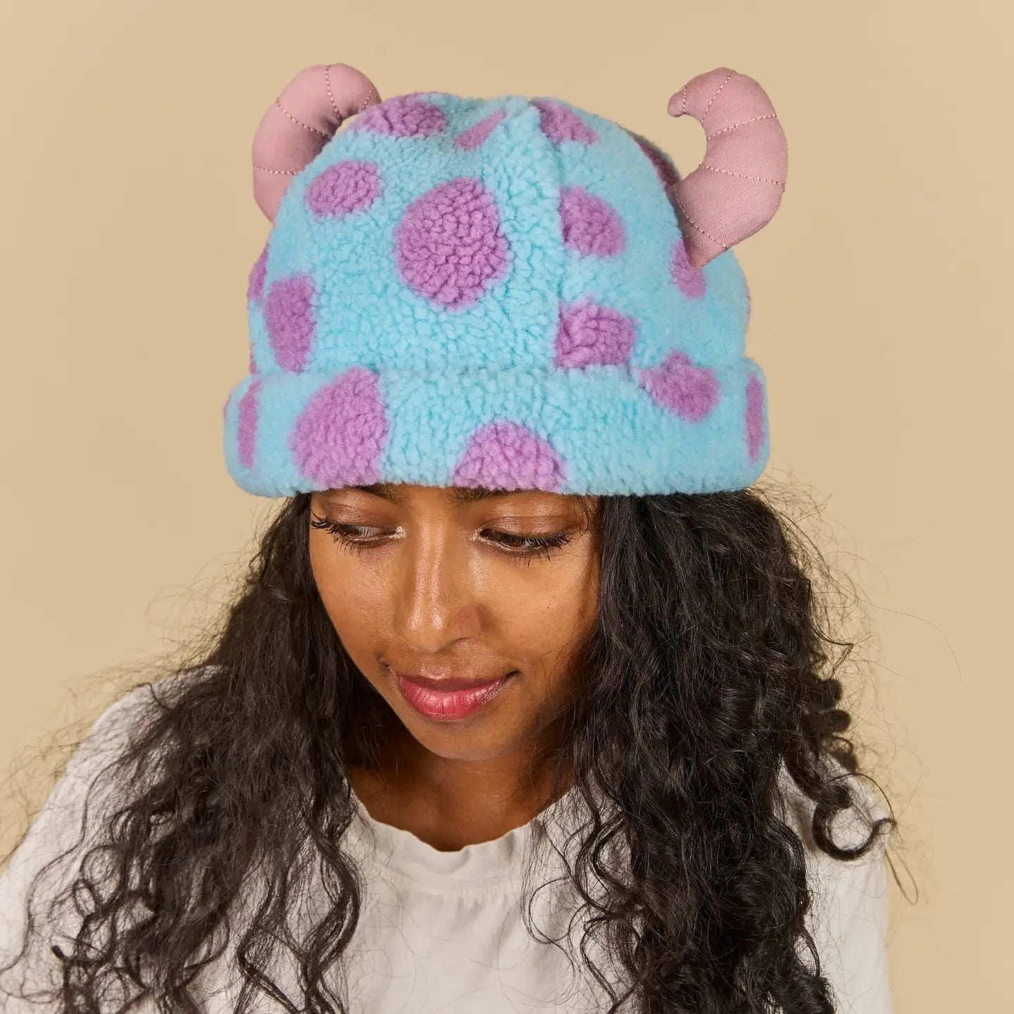 Person wearing a Sulley Sherpa Beanie with pink ears on a beige background