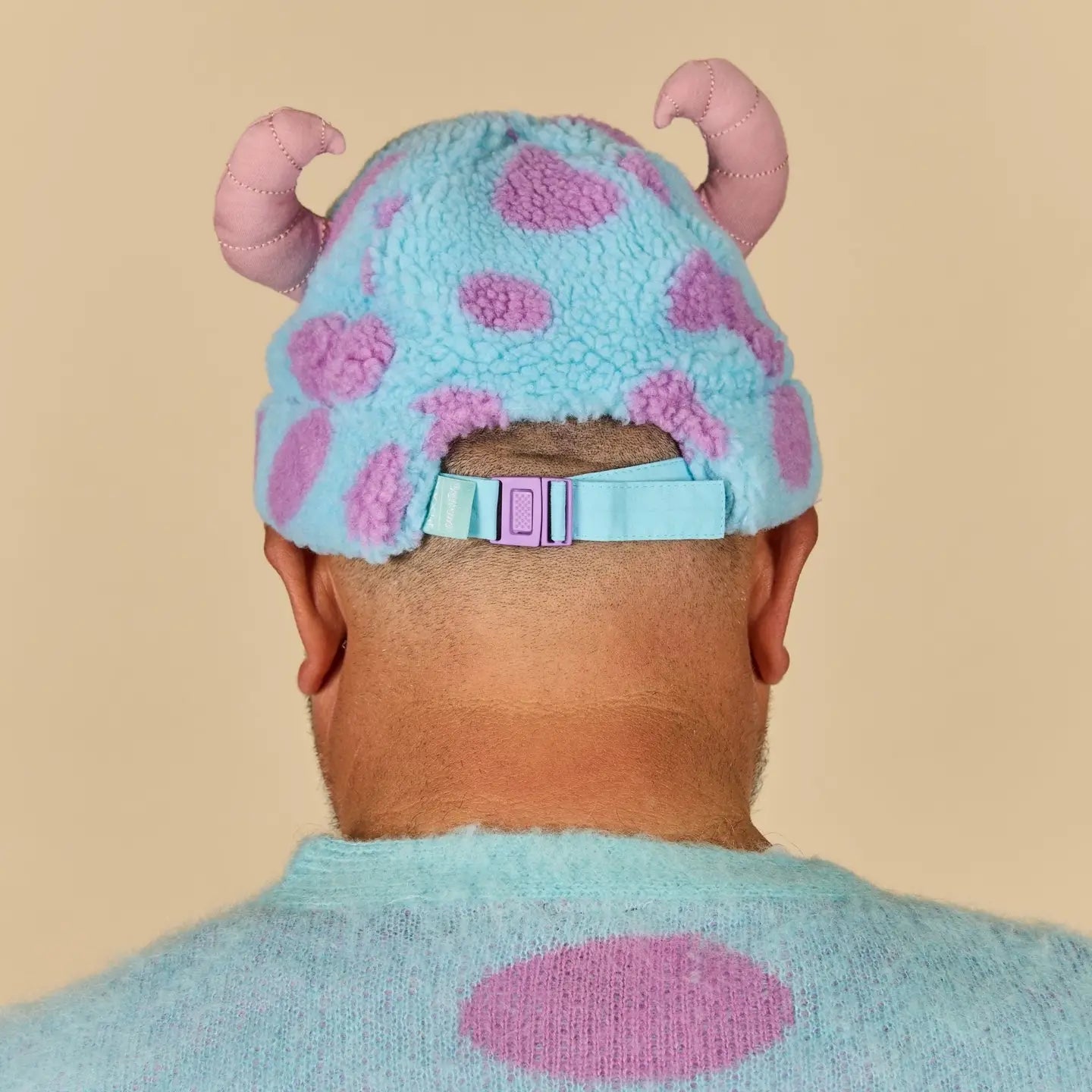 Person wearing a Sulley Sherpa Beanie with pink polka dots and pink ears on a beige background