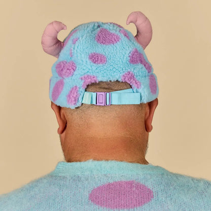 Person wearing a Sulley Sherpa Beanie with pink polka dots and pink ears on a beige background