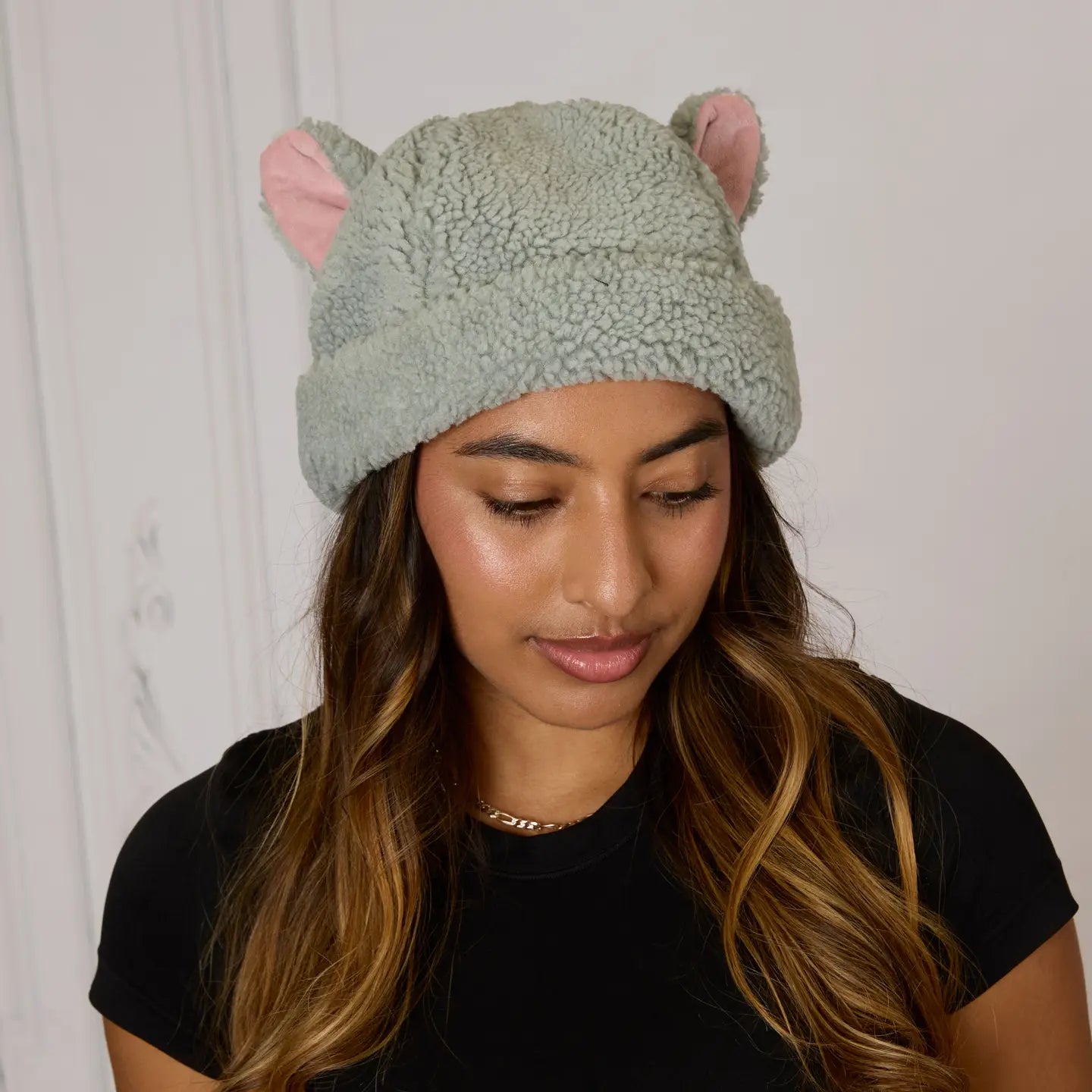 Woman wearing a grey The Aristocats Berloiz Sherpa beanie with pink ears against a white background