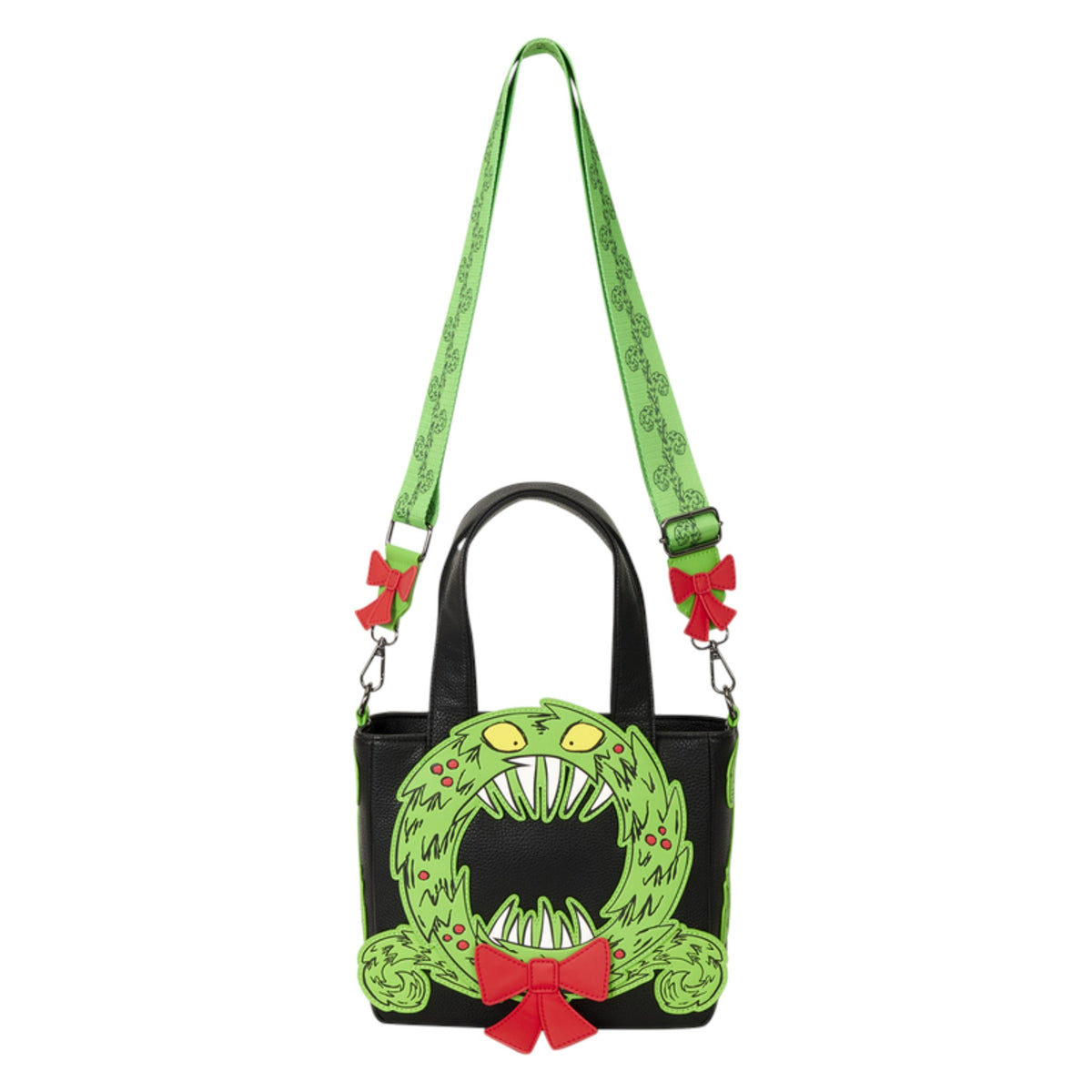 A black handbag with a green monster face design on the front, a green patterned shoulder strap, and red bow accents, shown on a plain white background.