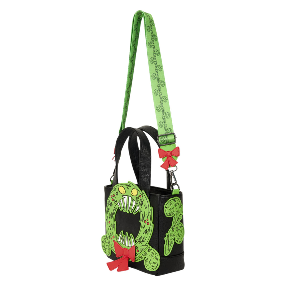 A black tote bag featuring a green monster face design on the front, a green patterned shoulder strap, and red bow accents, shown against a plain white background.