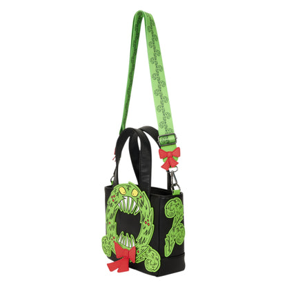 A black tote bag featuring a green monster face design on the front, a green patterned shoulder strap, and red bow accents, shown against a plain white background.