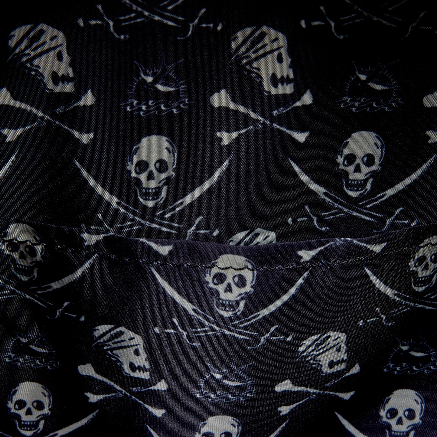 Close-up of inside of Loungefly Pirates of the Caribbean Jack Sparrow Cosplay Mini Backpack with black fabric with skull and crossbones pattern on a black background