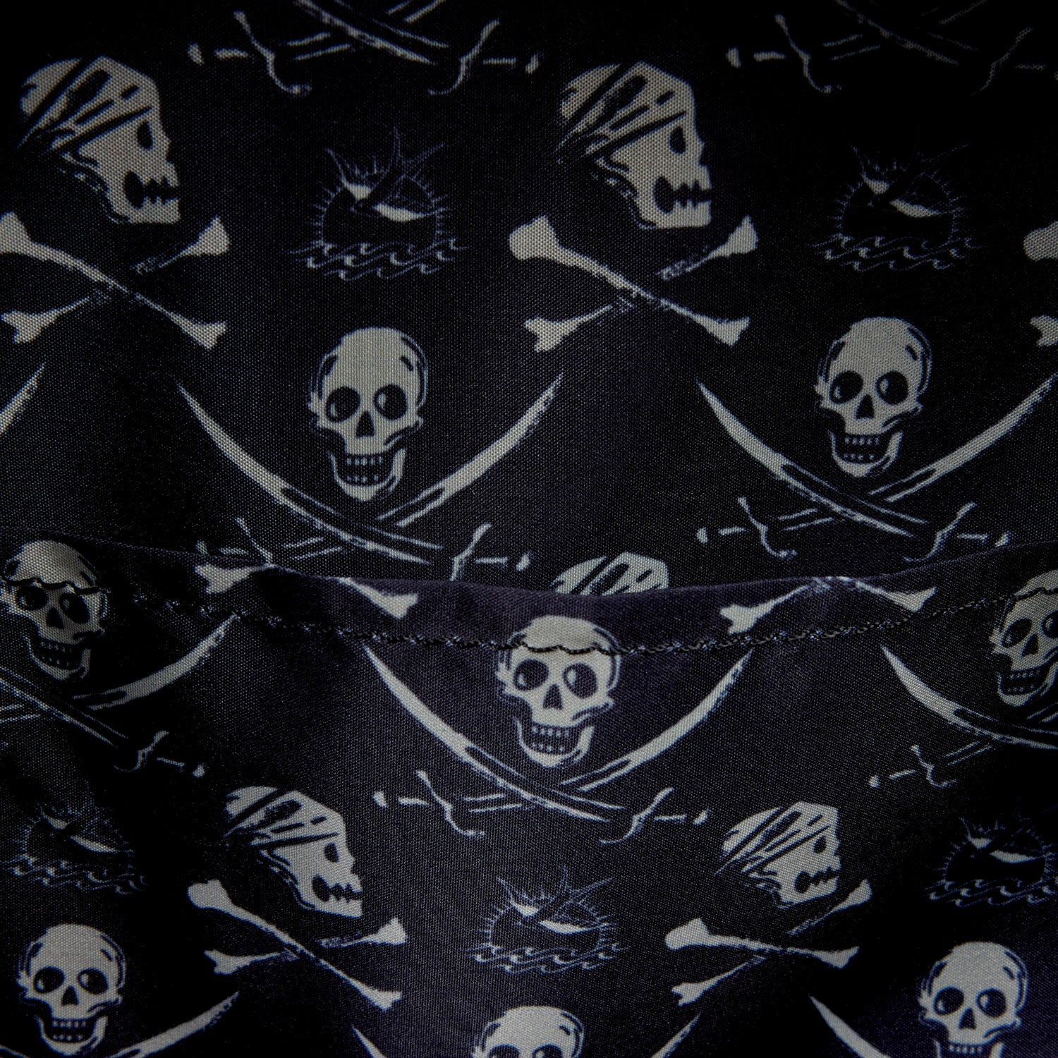 Close-up of inside of Loungefly Pirates of the Caribbean Jack Sparrow Cosplay Mini Backpack with black fabric with skull and crossbones pattern on a black background