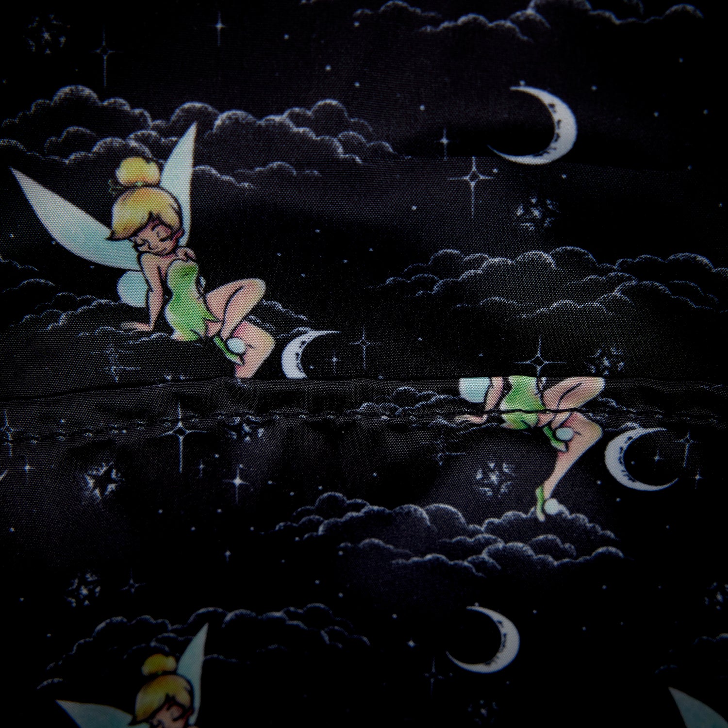 Inside of Loungefly Peter Pan Tinker Bell Pixie Dust Velvet Mini Backpack with Tinker Bell design on a black fabric background with moon and star patterns