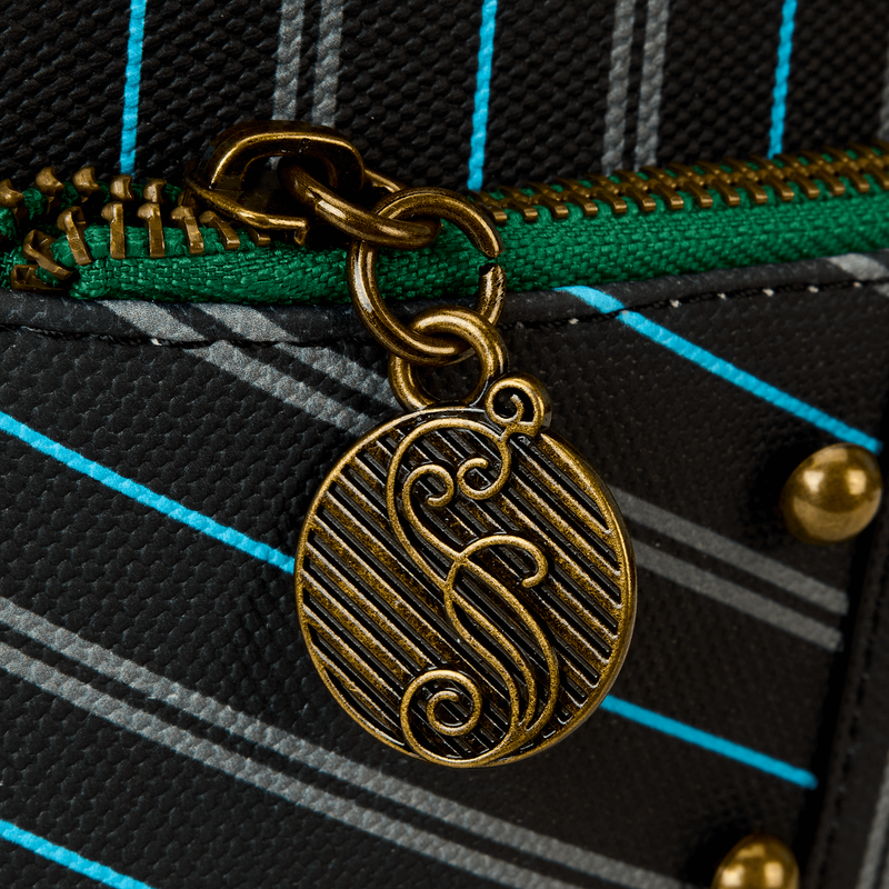 Close-up of a gold zipper charm with a logo on a plaid fabric background