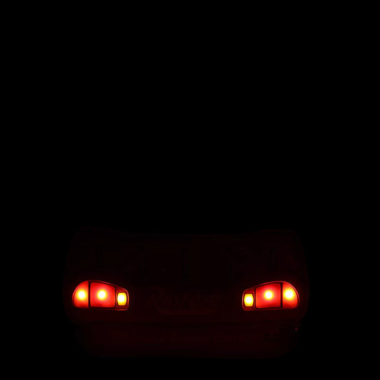 Two red headlights glowing on a dark background