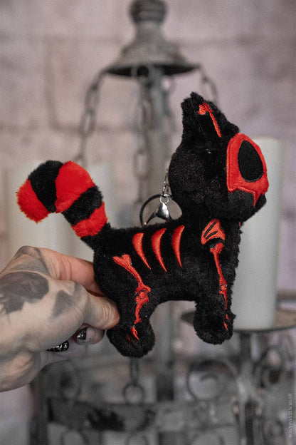 Black and red plush keychain held by a hand against a blurred background
