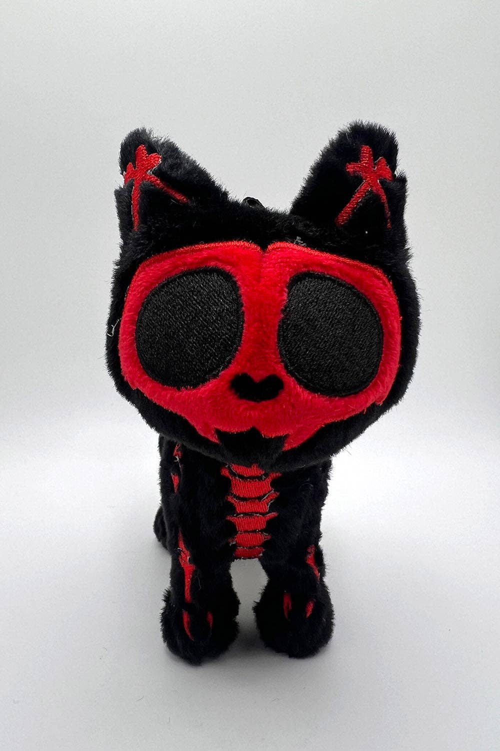 Black plush cat with red accents on a white background