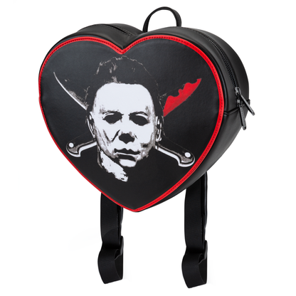 Tilted view of Michael Myers backpack with two knives in an X shape on red and black heart shaped backpack on a white background. 