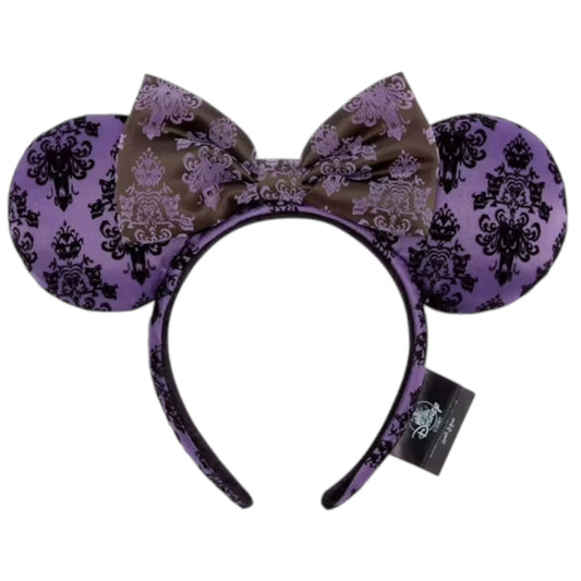 Purple and black haunted mansion patterned headband with bow on a white background
